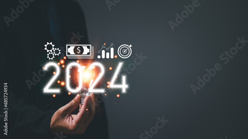Startup business concept. Man holding a light bulb. With a clear vision and strategic plan, a determined businessman navigates the trends of 2024, paving the way for a prosperous future.