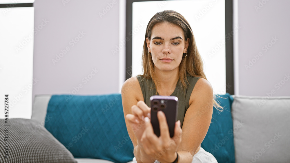 Young beautiful hispanic woman using smartphone sitting on sofa thinking at home Young beautiful hispanic woman using smartphone sitting on sofa thinking at home