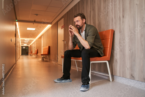 Sad man patient nervously impatiently waiting in the hospital lobby