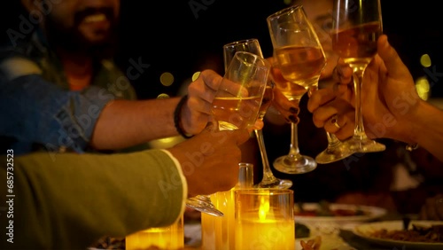 Close up shot hands starting new year party by holding clinking champagne glasses at night - concept of charismas celebration, friends gathering and entertainment.