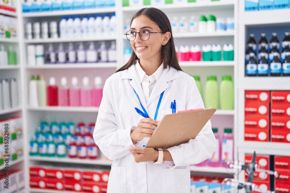 Young beautiful hispanic woman pharmacist writing on document at pharmacy Young beautiful hispanic woman pharmacist writing on document at pharmacy