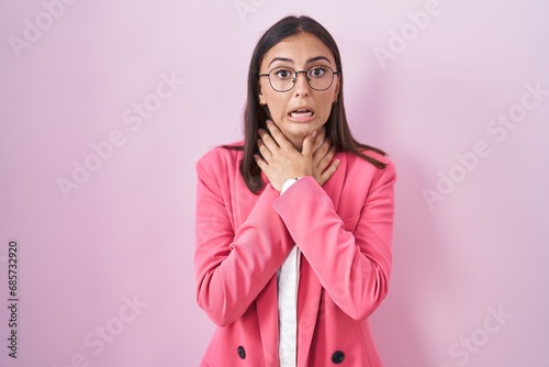 Young hispanic woman wearing business clothes and glasses shouting suffocate because painful strangle. health problem. asphyxiate and suicide concept.