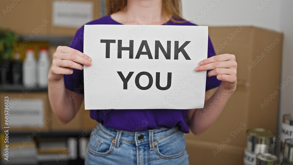 Young blonde woman volunteer holding thank you message at charity center Young blonde woman volunteer holding thank you message at charity center