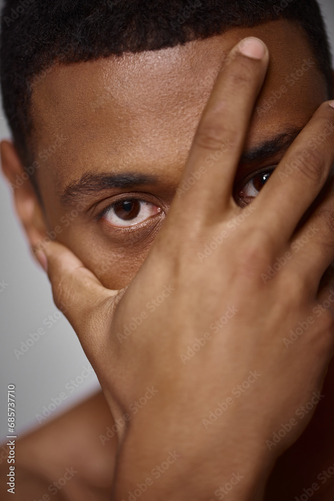 Fototapeta premium close up of handsome appealing african american man with hand in front of face, fashion concept