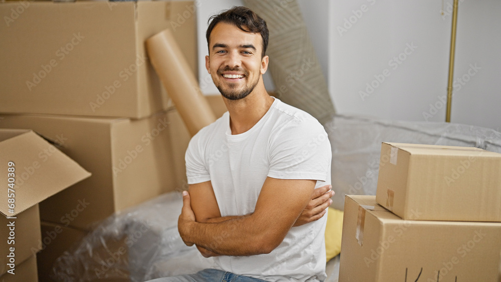 Young hispanic man smiling confident sitting on sofa with arms crossed gesture at new home Young hispanic man smiling confident sitting on sofa with arms crossed gesture at new home
