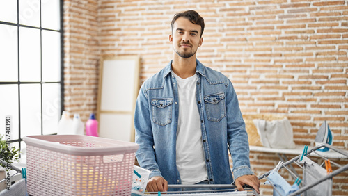 Young hispanic man smiling confident standing by clotheline at laundry room photo