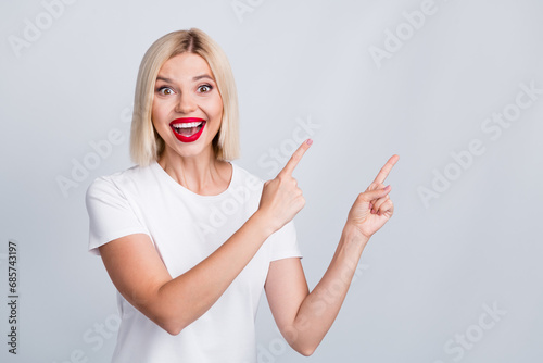 Photo of cheerful satisfied girl wearing trendy clothes presenting empty space seasonal proposition isolated on grey color background