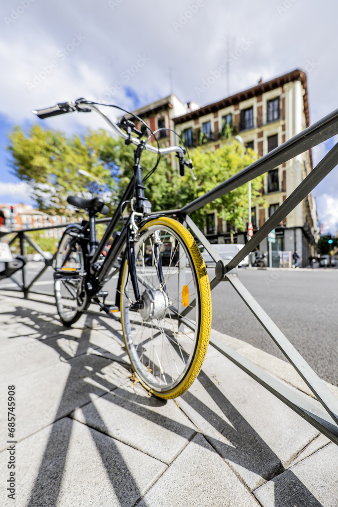 A stroller bicycle leaning on a metal railing on an urban street