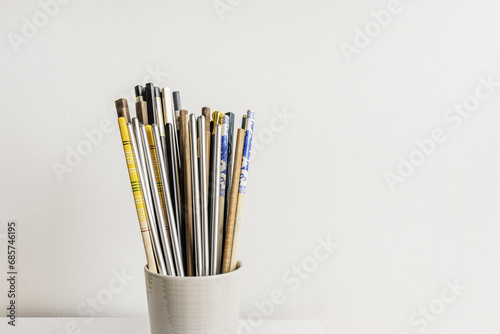 A light porcelain container filled with wooden eating chopsticks and other materials