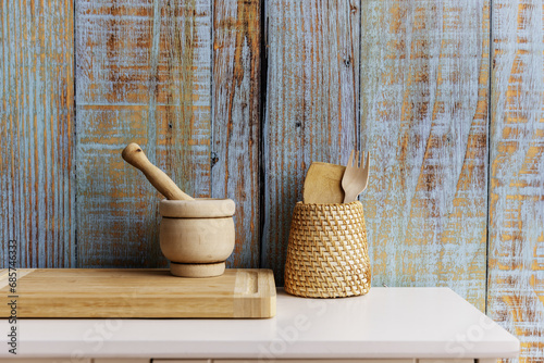 wooden and fiber kitchen utensils on a small white wooden sideboard with blue planks background