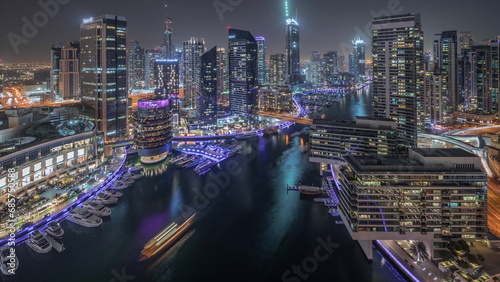 Aerial view to Dubai marina skyscrapers around canal with floating boats night timelapse