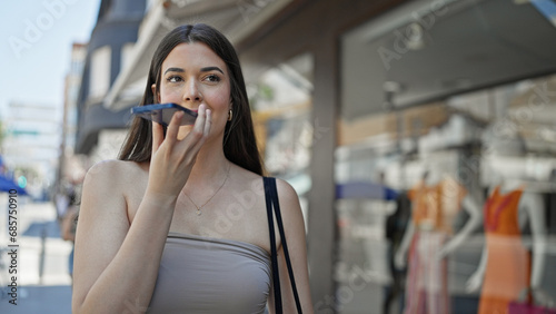 Young beautiful hispanic woman sending voice message with smartphone at street