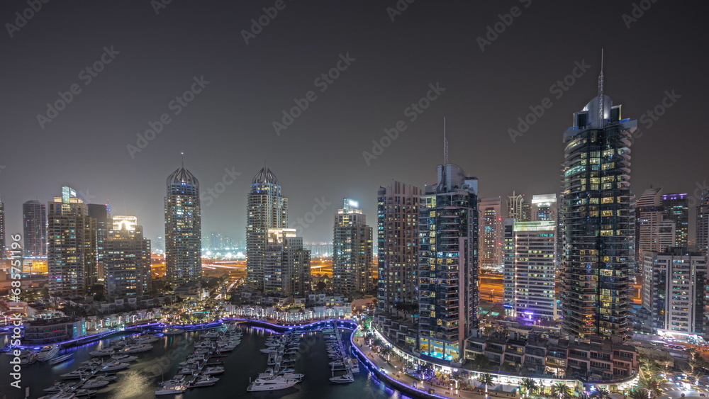 Naklejka premium Panorama showing Dubai marina tallest skyscrapers and yachts in harbor aerial night timelapse.