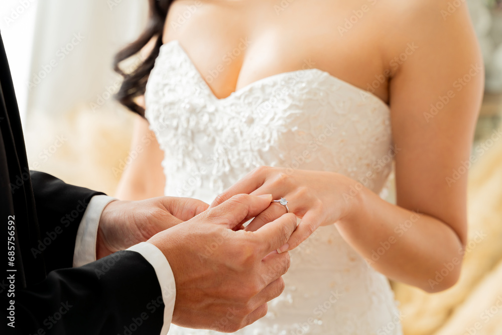 Close-up of groom placing diamond ring on bride's finger, symbolizing eternal love and commitment - wedding ceremony concept Close-up of groom placing diamond ring on bride's finger, symbolizing eternal love and commitment - wedding ceremony concept