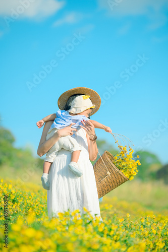 Mother with little child in flower blooming garden. woman with son in green leaves,happy family outdoors in spring