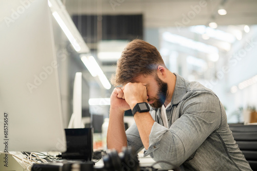 Stressed male entrepreneur sitting at desk while having a headache