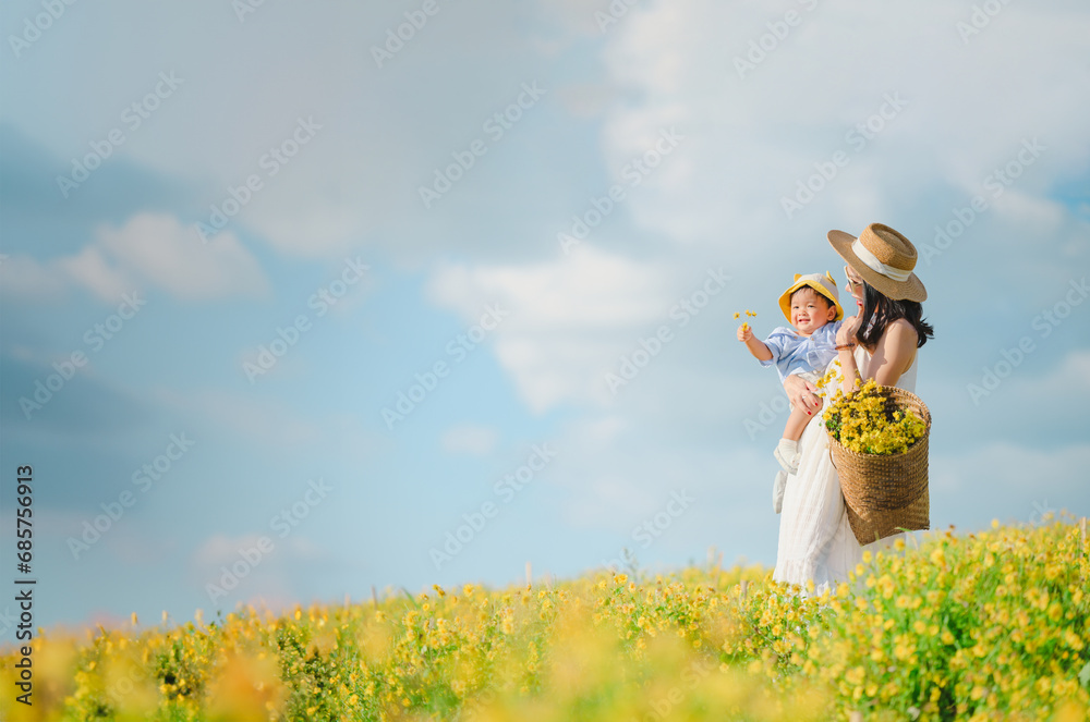 Mother with little child in flower blooming garden. woman with son in green leaves,happy family outdoors in spring