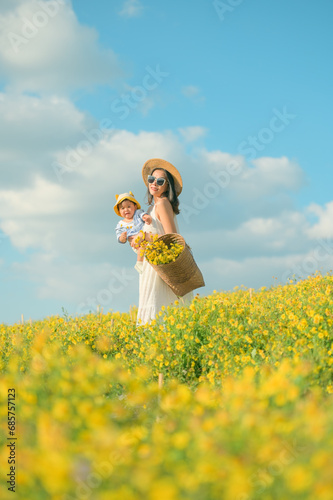 Mother with little child in flower blooming garden. woman with son in green leaves,happy family outdoors in spring © grooveriderz