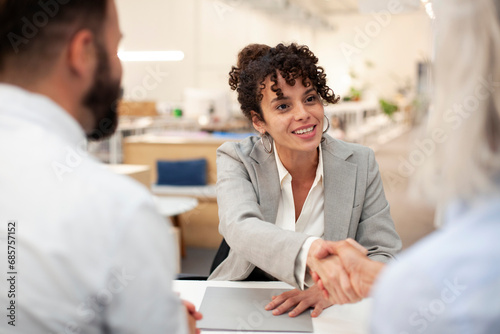 Female bank worker shaking hands with clients after meeting