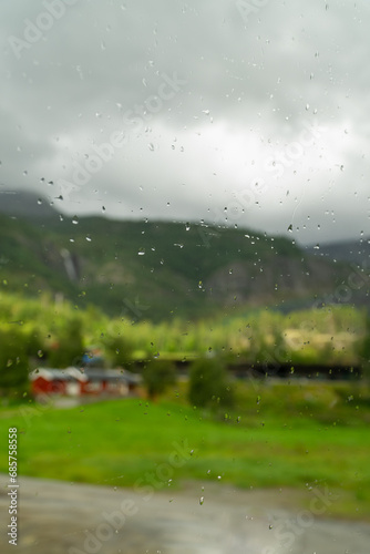 Out of focus view through rainy glass of red Scandinavian house