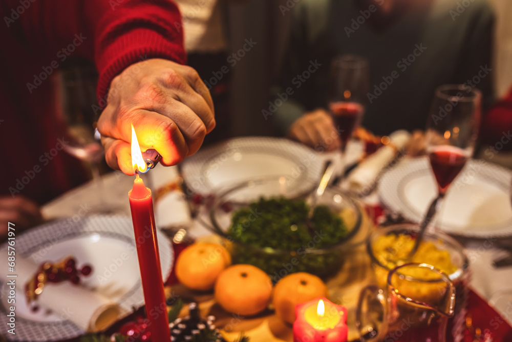 Lighting a candle on the dining table. Family having Christmas dinner.