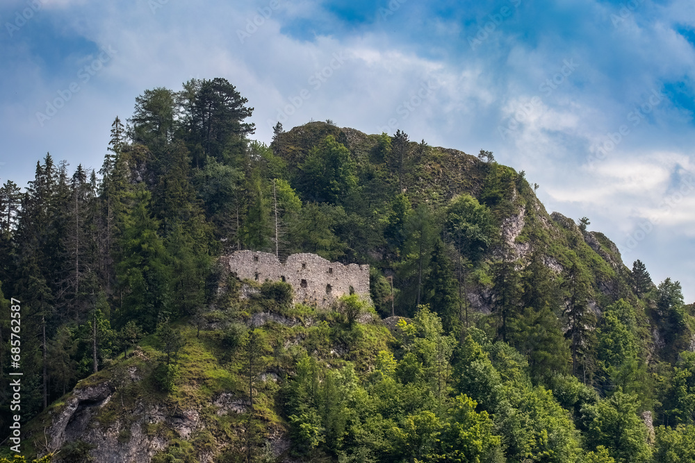 The ruins of the Vršatec castle standing on a high rock. The castle is surrounded by trees.