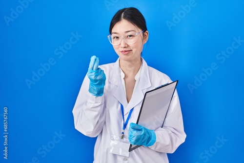 Chinese young woman working at scientist laboratory doing money gesture with hands  asking for salary payment  millionaire business