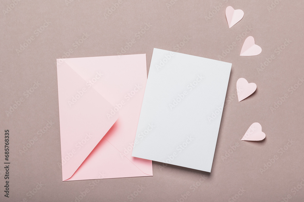 Pink envelope and blank form on a brown background. Paper pink hearts. Valentine's Day concept. Pink envelope and blank form on a brown background. Paper pink hearts. Valentine's Day concept.