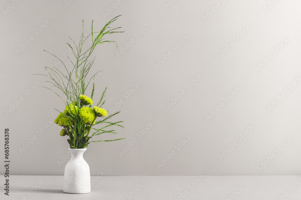 A bouquet of small green chrysanthemums in a ceramic mini vase on a white table. Women's workplace, mockup, congratulations. A bouquet of small green chrysanthemums in a ceramic mini vase on a white table. Women's workplace, mockup, congratulations.
