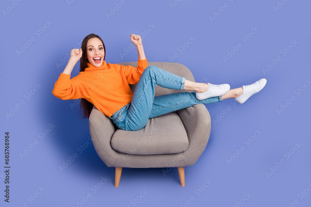 Full body photo of lady in knitted jumper lying armchair relaxing watching football match celebrating isolated on purple color background Full body photo of lady in knitted jumper lying armchair relaxing watching football match celebrating isolated on purple color background