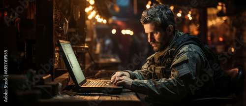 Portrait of soldier wearing a military uniform, operating at his computer. Soldier operating laptop photo
