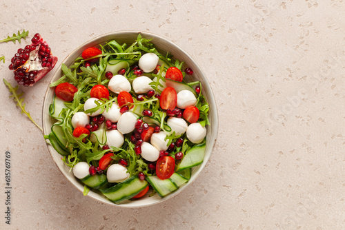 Vegetable salad with cheese and pomegranate grains on a light background. Top view