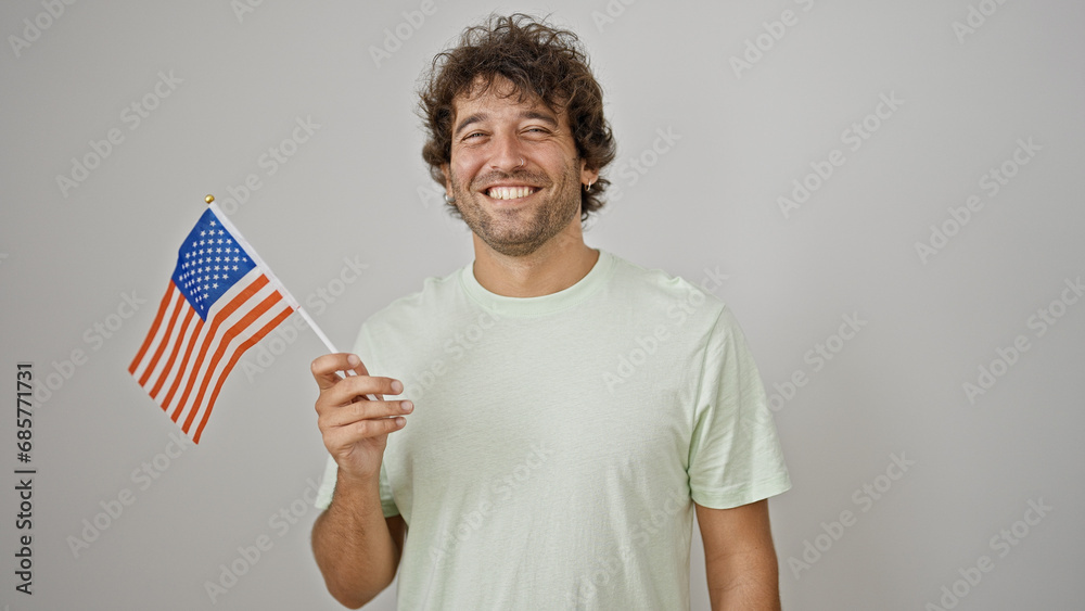 Young hispanic man smiling confident holding united states flag over isolated white background Young hispanic man smiling confident holding united states flag over isolated white background