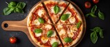 Pizza Margherita on a background of black stone, top view. Pizza Margherita with tomatoes and basil