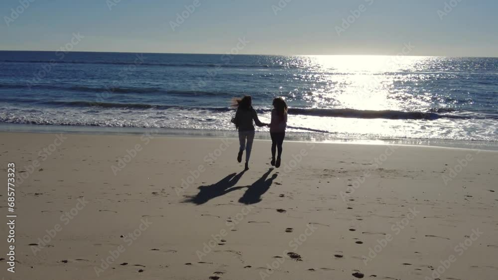 Happy girlfriends running on sandy beach near sea Happy girlfriends running on sandy beach near sea