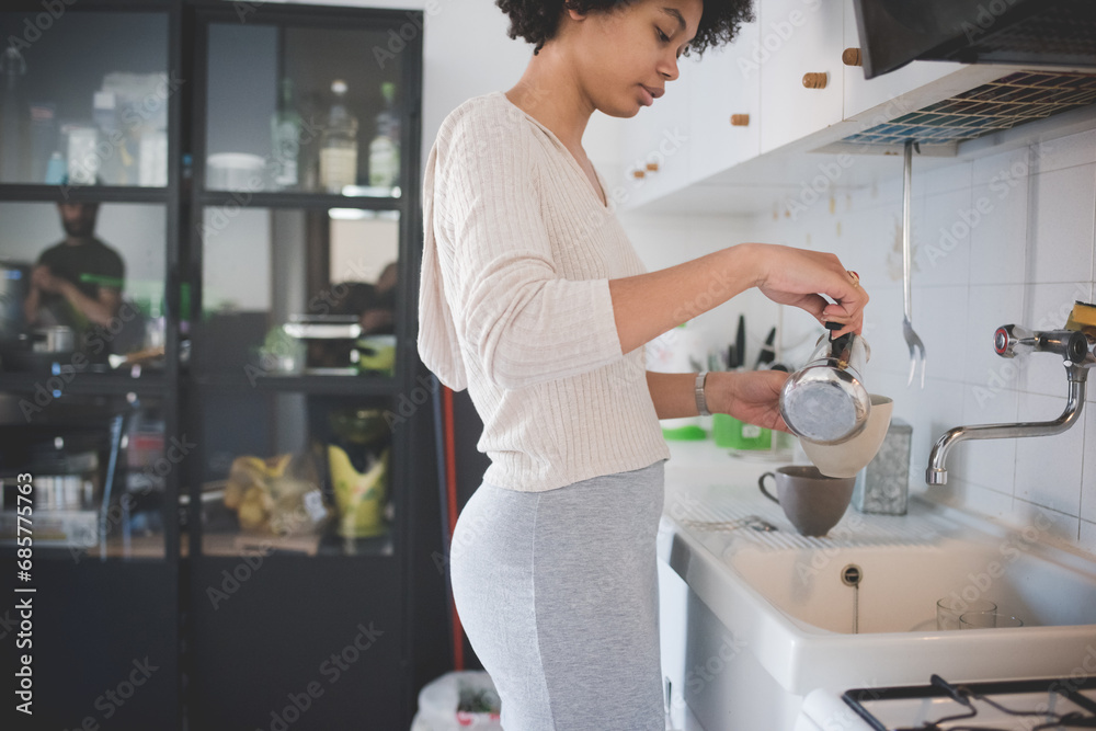 Young multiethnic woman at home preparing coffee using moka Young multiethnic woman at home preparing coffee using moka