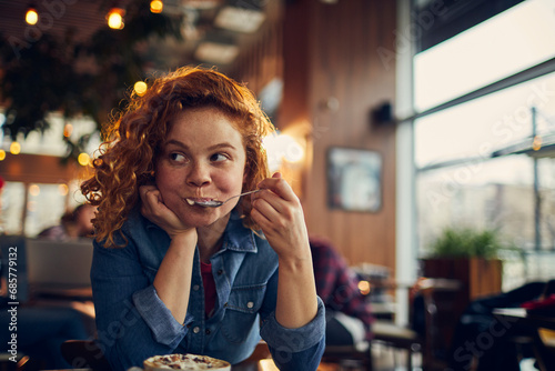 Young woman enjoying sweet treat in cozy cafe photo