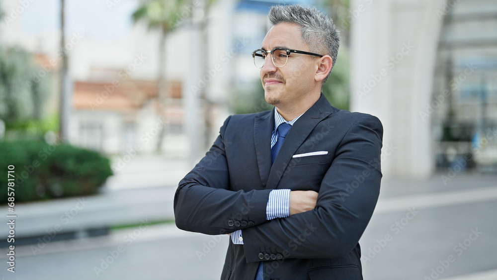 Young hispanic man business worker standing with serious face and arms crossed gesture at street Young hispanic man business worker standing with serious face and arms crossed gesture at street