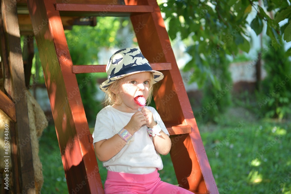 A girl licking with a tongue sweet scrapper lollipop while swinging on a tree