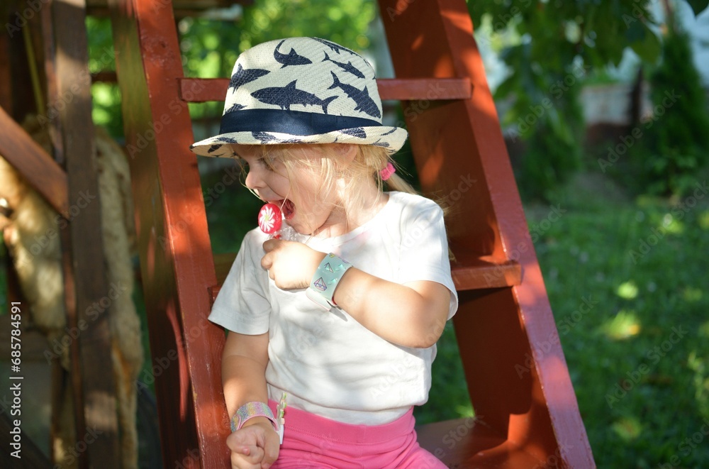 A girl licking with a tongue sweet scrapper lollipop while swinging on a tree