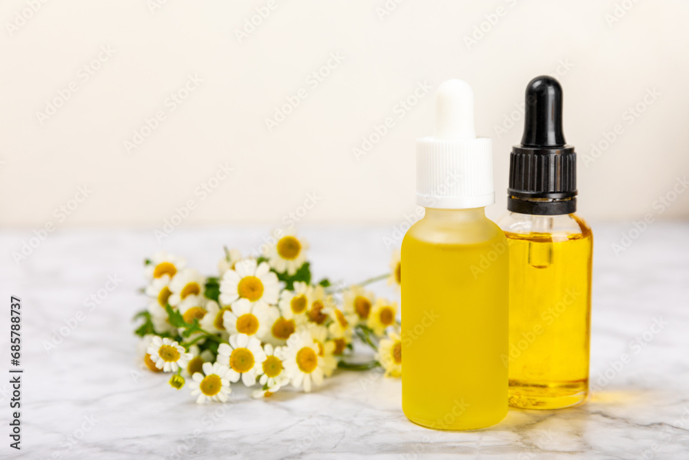 Glass bottle with chamomile essential oil on an old wooden background. Chamomile flowers, close up. Aromatherapy, spa and herbal medicine ingredients. Beauty concept.Copy space. Natural cosmetic Glass bottle with chamomile essential oil on an old wooden background. Chamomile flowers, close up. Aromatherapy, spa and herbal medicine ingredients. Beauty concept.Copy space. Natural cosmetic