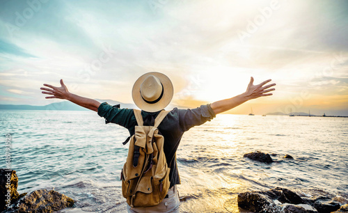 Happy man raising arms up enjoying sunset on the beach - Delightful traveler standing with hands up looking morning sunrise - Self care, traveling, wellness and healthy life style concept #685793525