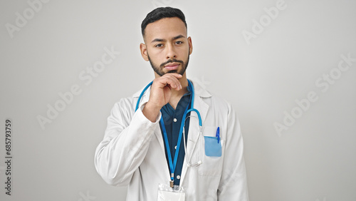 Young hispanic man doctor standing with doubt expression thinking over isolated white background