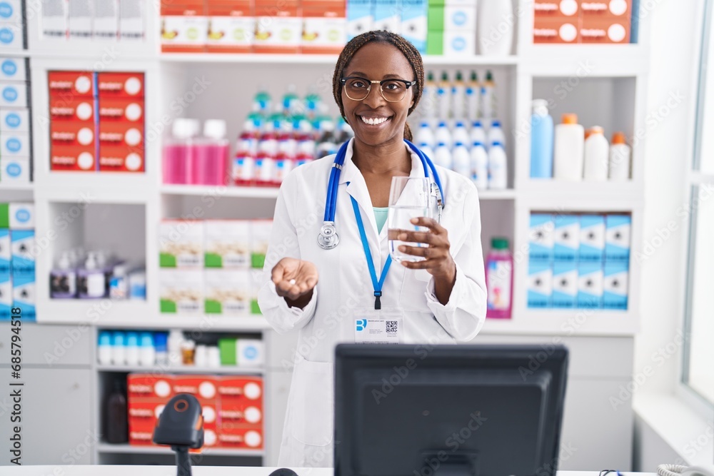 African american woman pharmacist holding pill and glass of water at pharmacy African american woman pharmacist holding pill and glass of water at pharmacy
