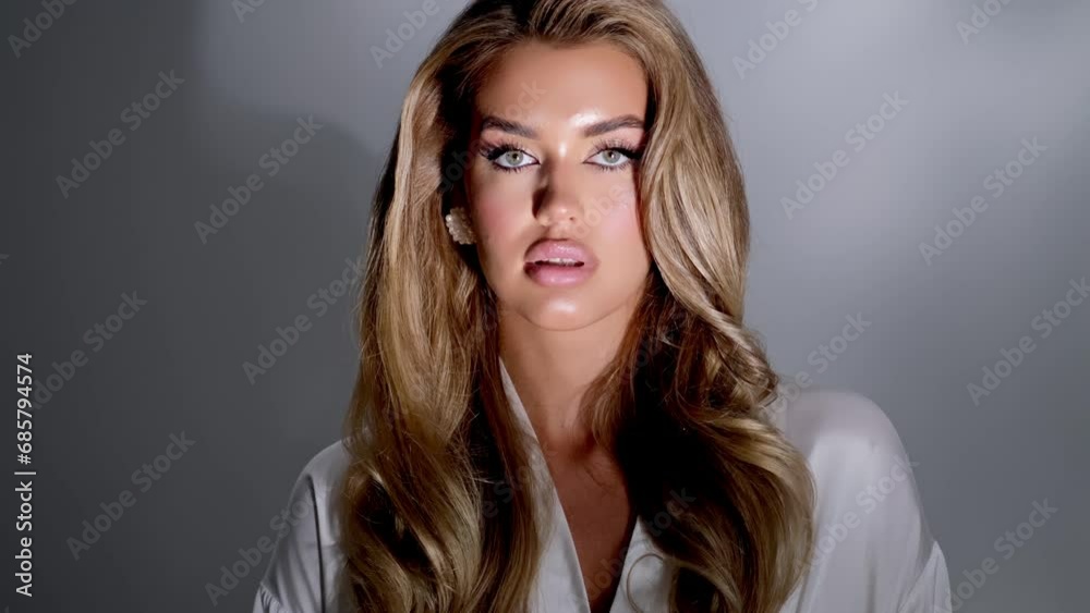 Close-up portrait of a young luxurious sexy woman in curlers and bright makeup. A blonde woman moves against a light background. Beauty, fashion and style concept. Close-up portrait of a young luxurious sexy woman in curlers and bright makeup. A blonde woman moves against a light background. Beauty, fashion and style concept.