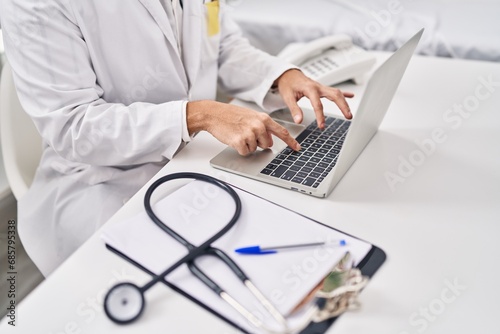 Young hispanic man doctor using laptop at clinic