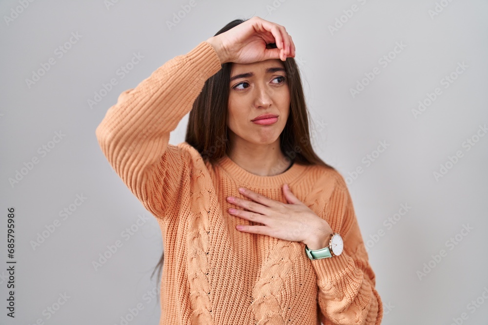 © Krakenimages.com - Young brunette woman standing over white background touching forehead for illness and fever, flu and cold, virus sick