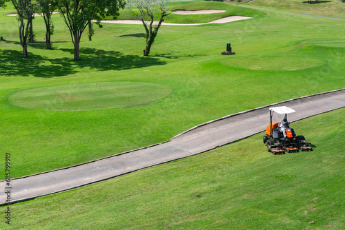 A Man driving professional lawn mower mows the grass in the golf course