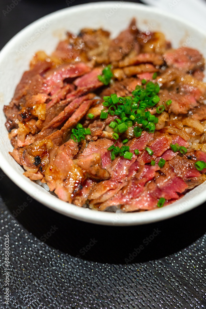 Japanese bowl of rice topped with beef steak medium rare served in restaurant. Japanese bowl of rice topped with beef steak medium rare served in restaurant.