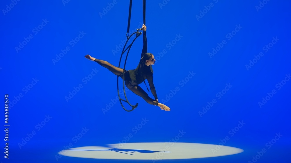 Rhythmic gymnastics girl performs the scum on one arm in the air on a ...